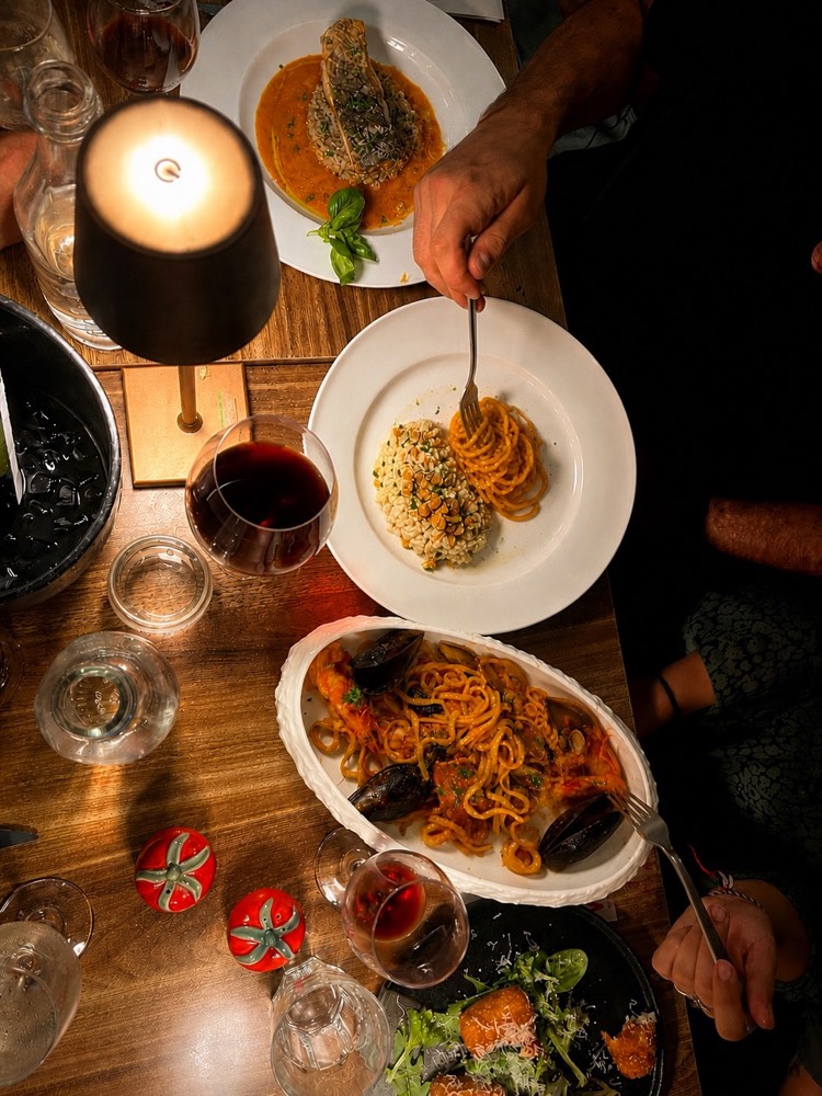 Dinner by candlelight at Vitalia's: pasta, wine and hands reaching across the table