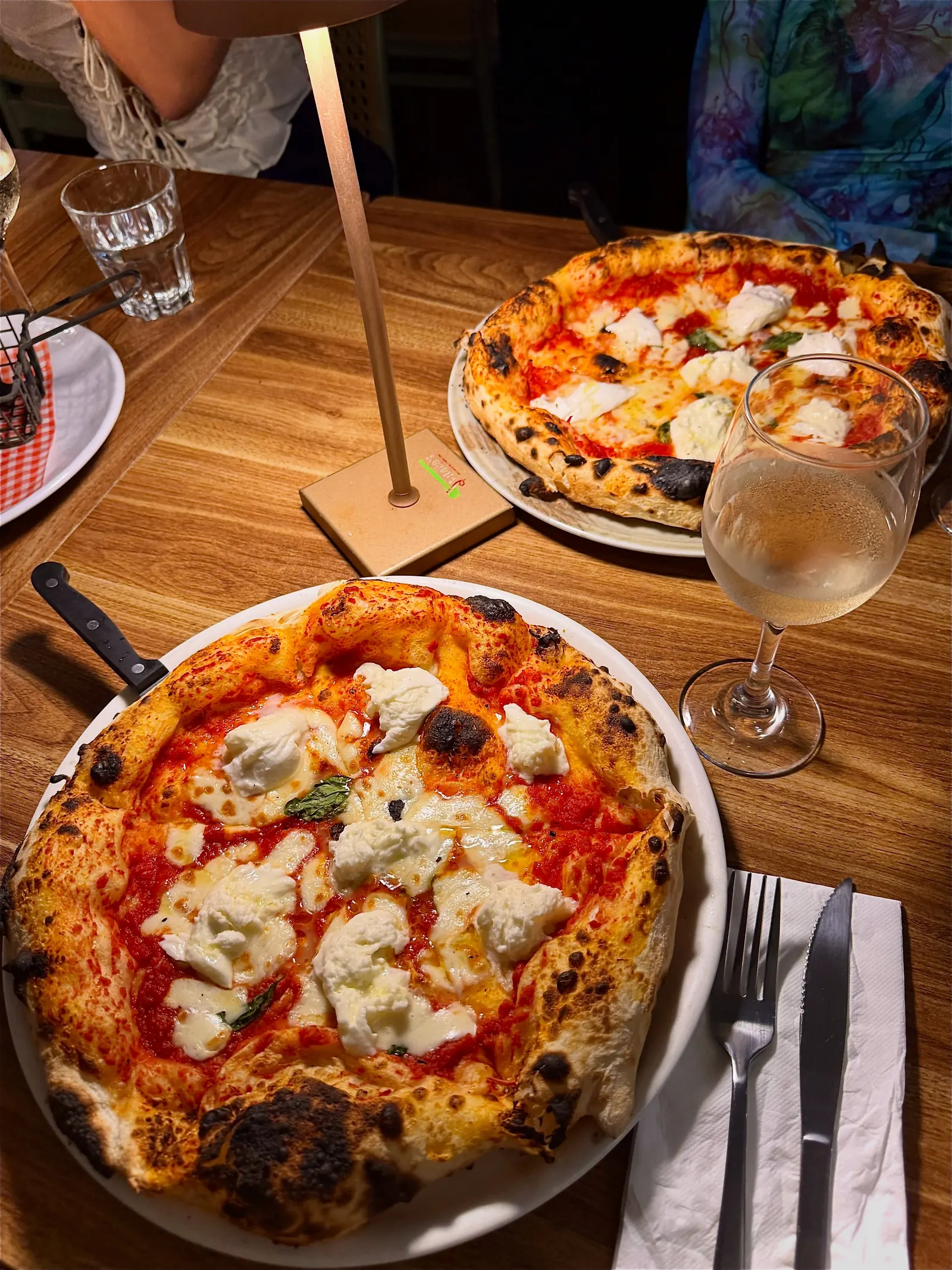 Two burrata pizzas with a blistered Neapolitan crust on a table at Vitalia's